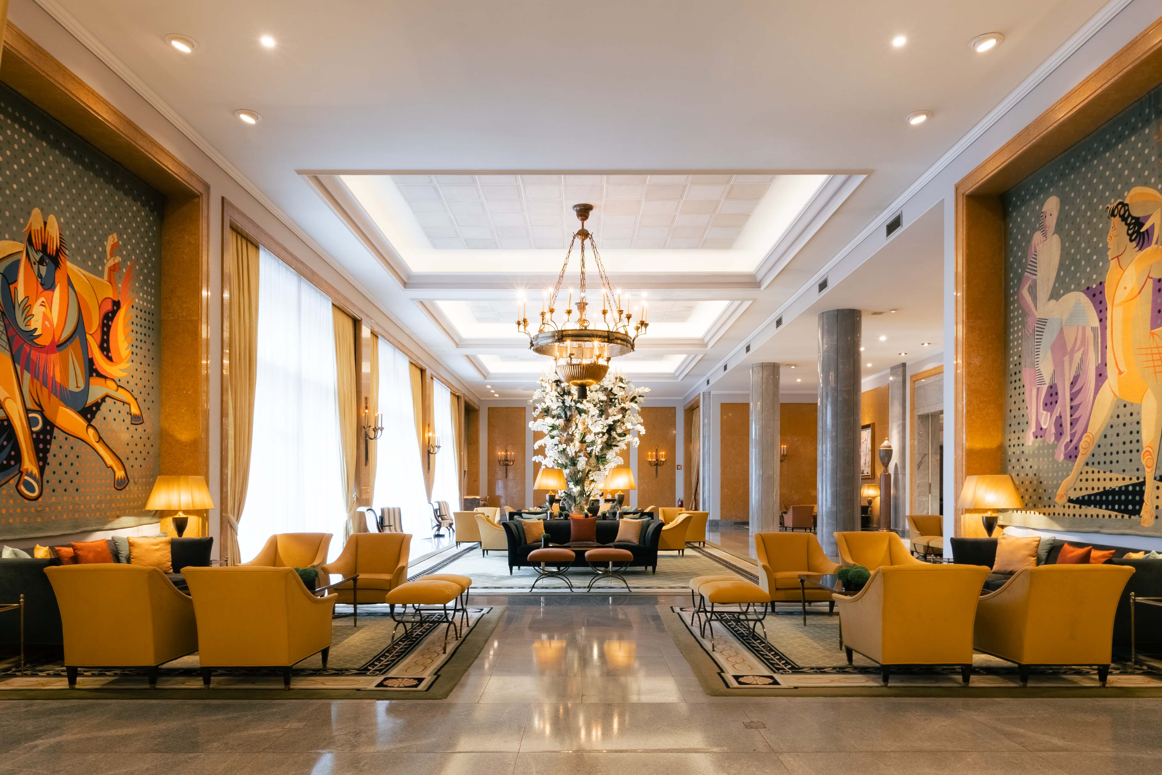 Four Seasons Lisbon lobby with yellow armchairs, large central flower arrangement and mural-lined walls, photographed by luxury hotel photographer in Lisbon