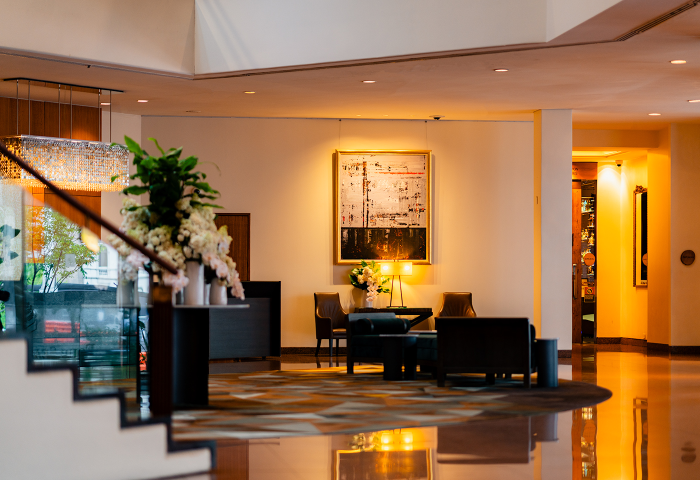 Four Seasons Sydney lobby lounge with staircase foreground, floral arrangement, modern seating area, and warm ambient lighting.