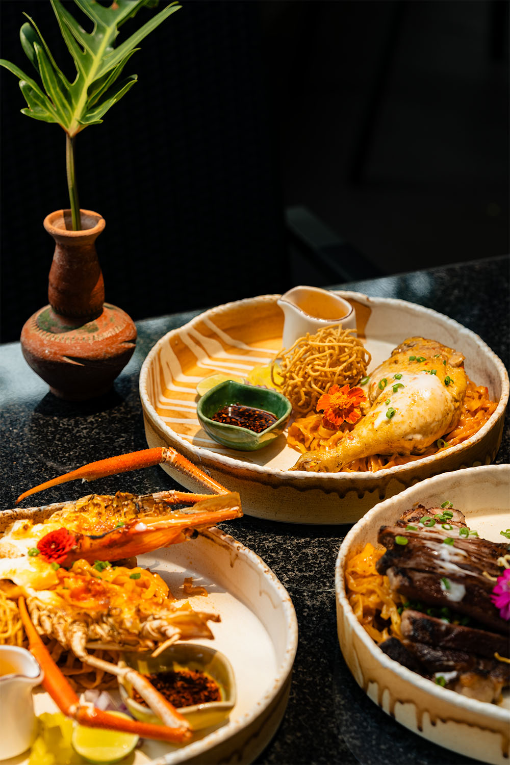 Northern Thai khao soi dishes with lobster, chicken, and braised beef served in handmade ceramic bowls at Anantara Chiang Mai Resort restaurant