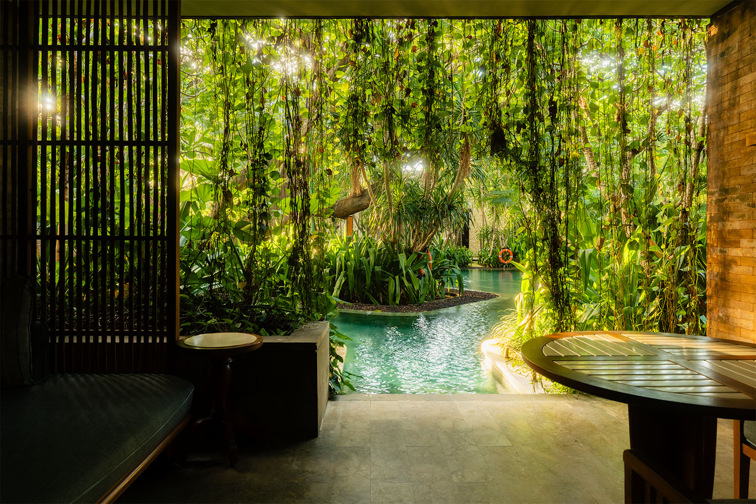 Villa terrace opening directly onto a jungle pool surrounded by cascading vines and tropical foliage at Andaz Bali Sanur