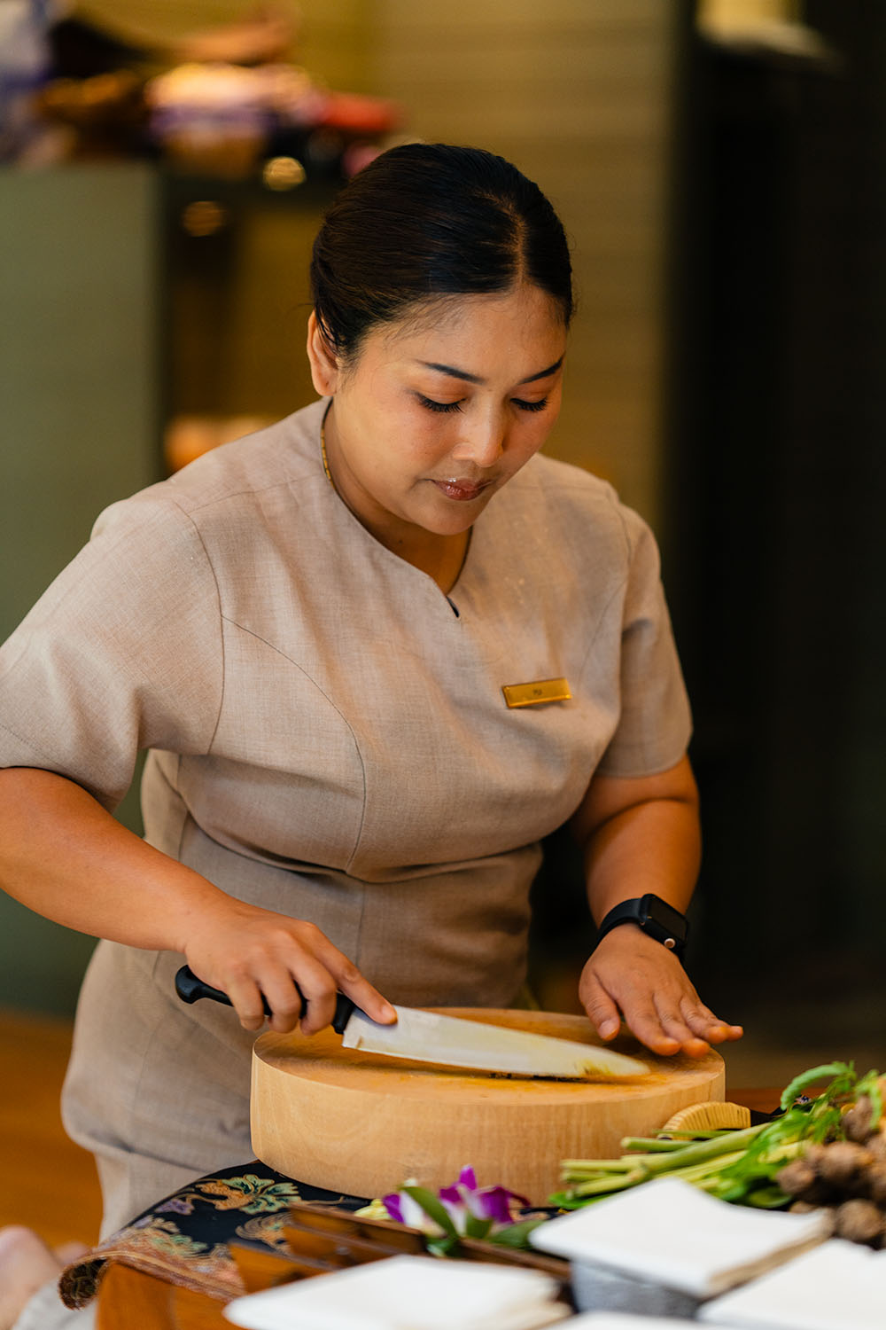 Spa therapist preparing fresh herbal compress ingredients with lemongrass and galangal at Conrad Koh Samui