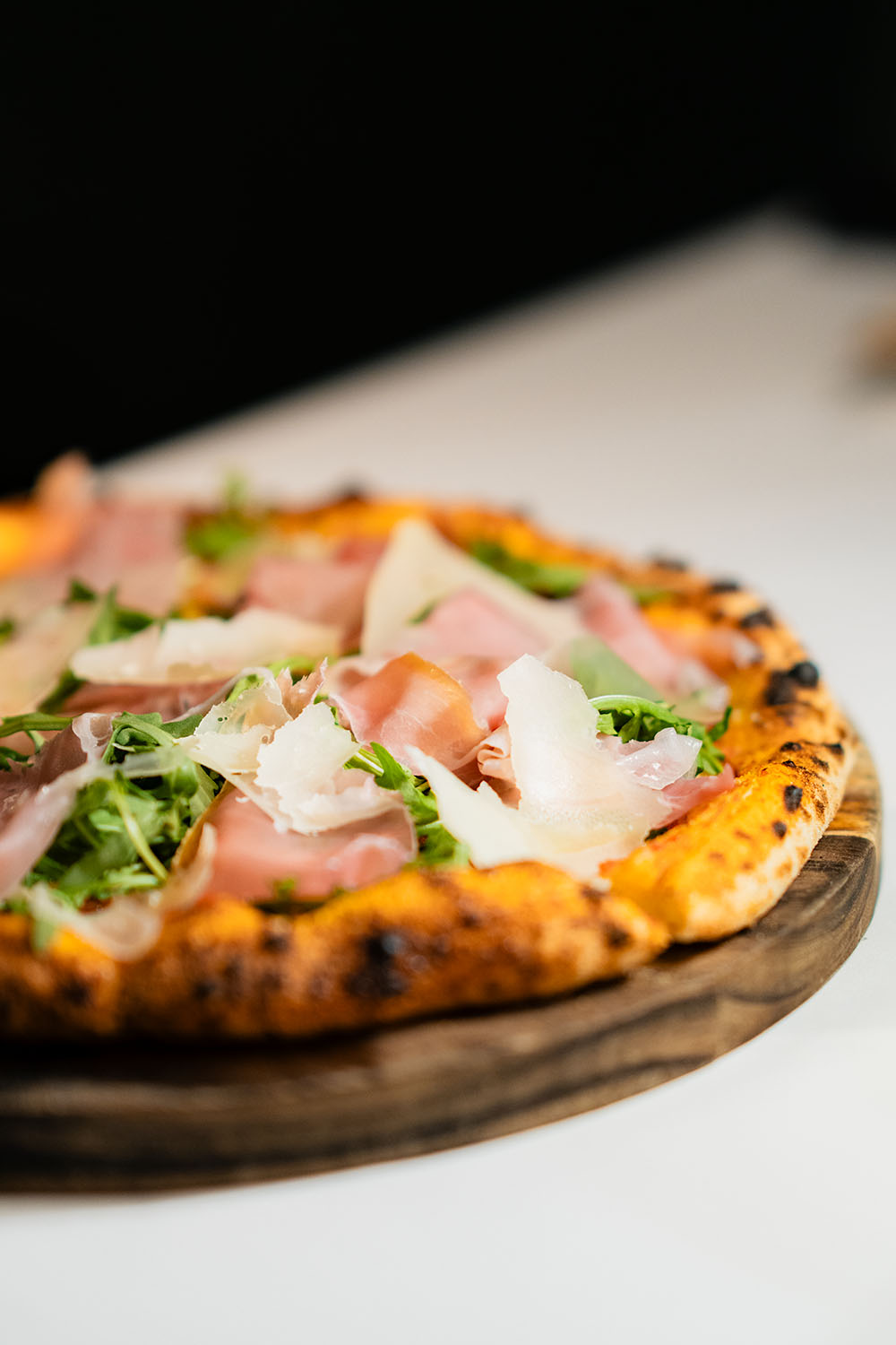Wood-fired pizza with prosciutto, rocket, and shaved parmesan on a rustic board at Grand Hyatt Erawan Bangkok