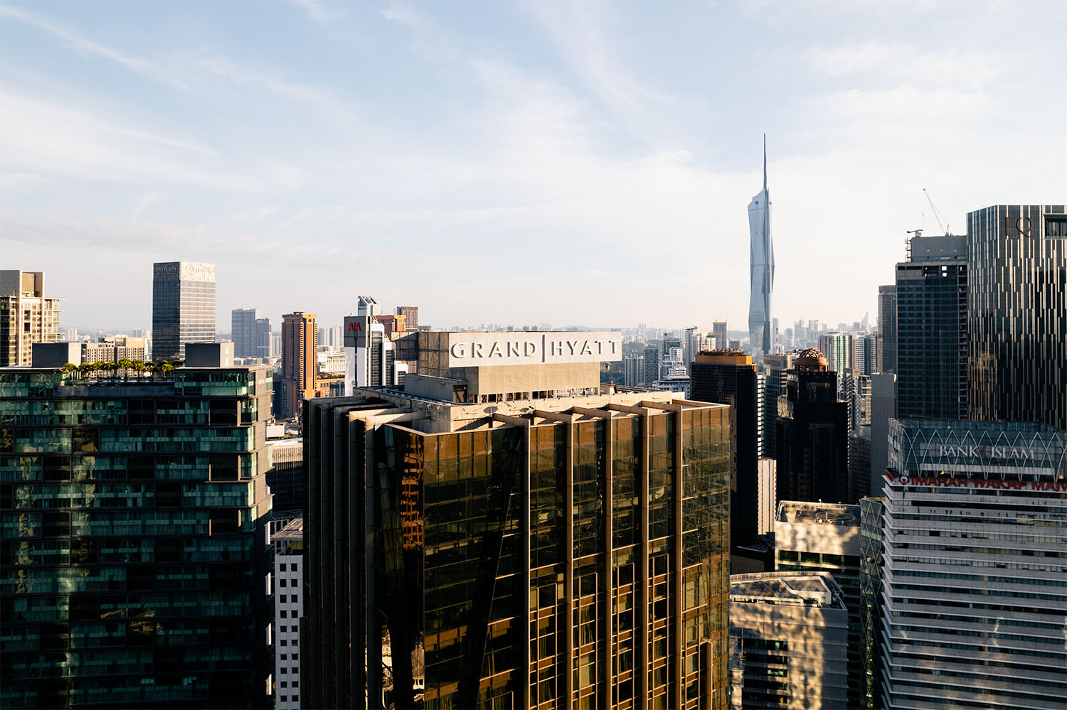 Drone view of Grand Hyatt Kuala Lumpur rooftop signage against the city skyline with Merdeka 118 tower in the background