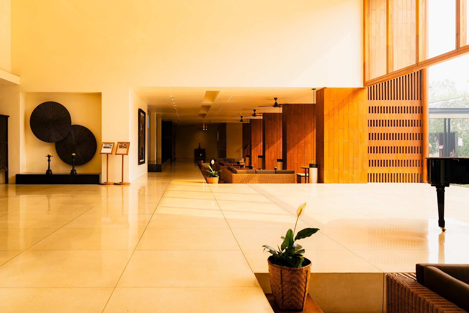 Anantara Chiang Mai Resort lobby at golden hour, warm light across polished marble floors, teak wall paneling, and grand piano