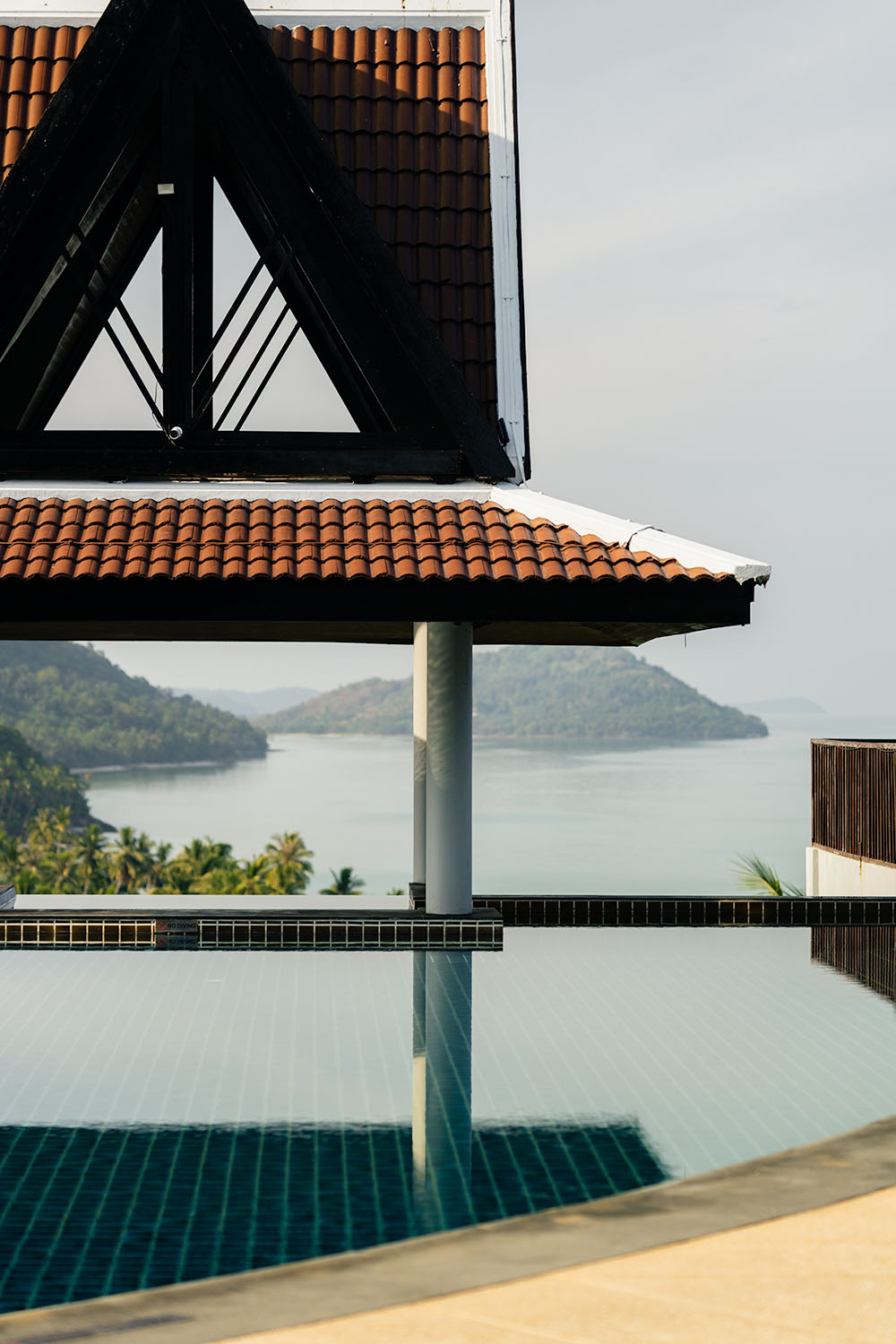 Hilltop infinity pool at InterContinental Koh Samui Resort reflecting terracotta roof tiles and island-dotted bay beyond