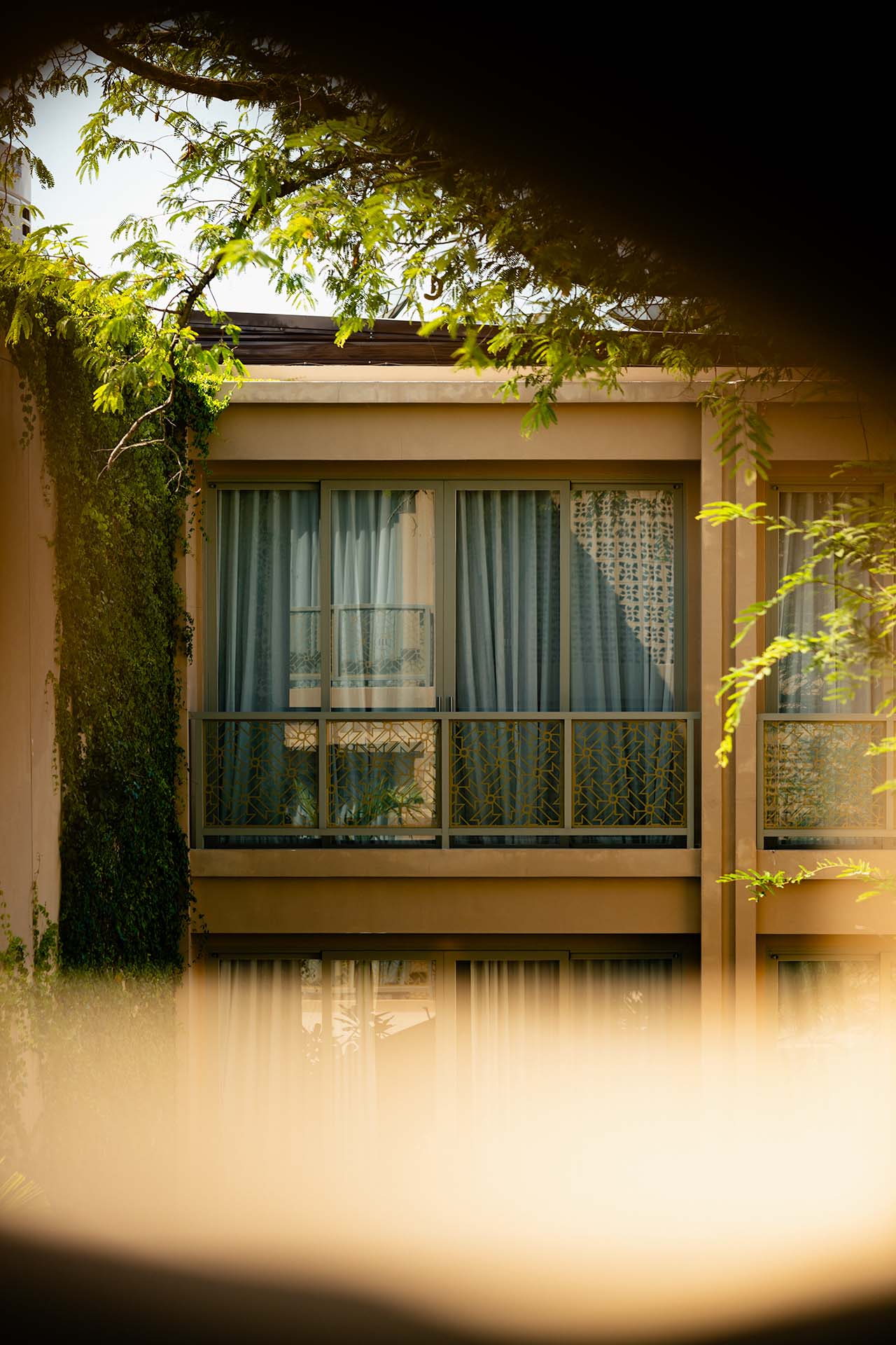 Exterior view of Marasca Koh Samui guest room balconies framed by tropical foliage and warm afternoon light — Small Luxury Hotels
