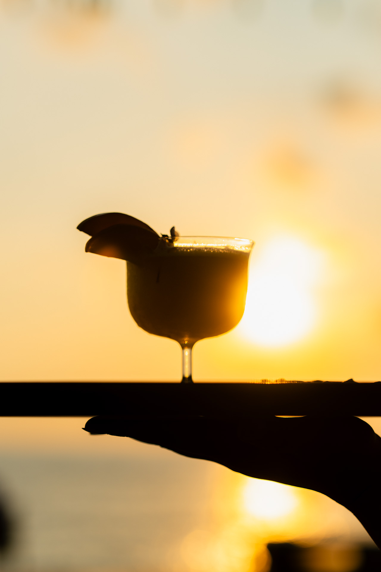 Cocktail glass silhouetted against a burning orange sunset over the Gulf of Thailand at The Retreat Koh Chang