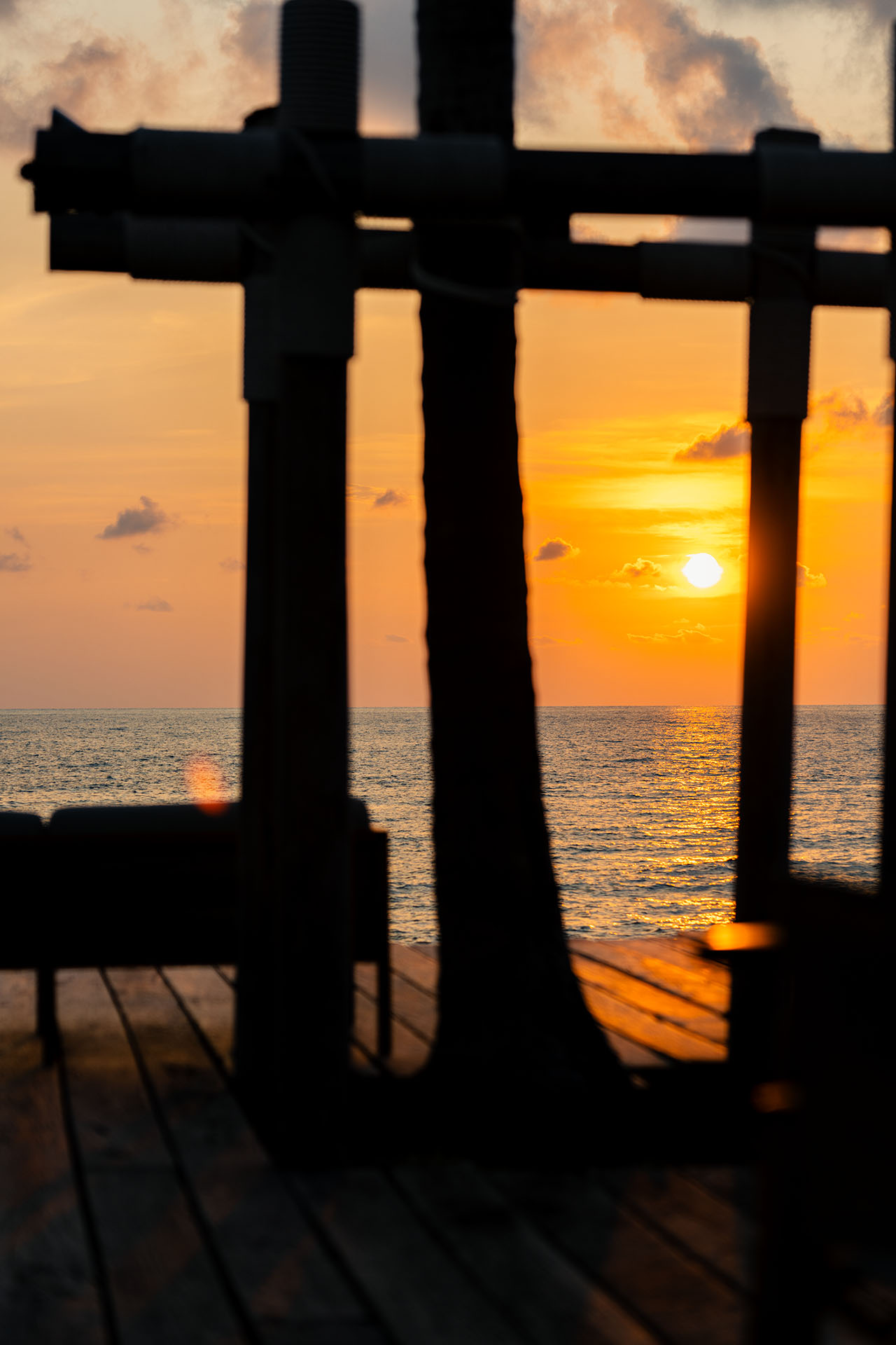 Fiery sunset framed through silhouetted timber pier posts over the Gulf of Thailand at The Retreat Koh Chang