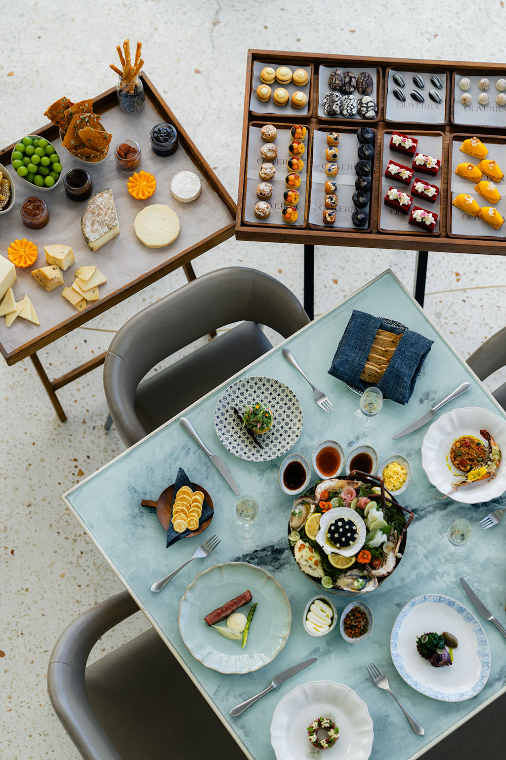 Overhead view of brunch spread at Umana Bali with seafood tower, cheese board, and Oliverra pastry selection on marble and wood tables